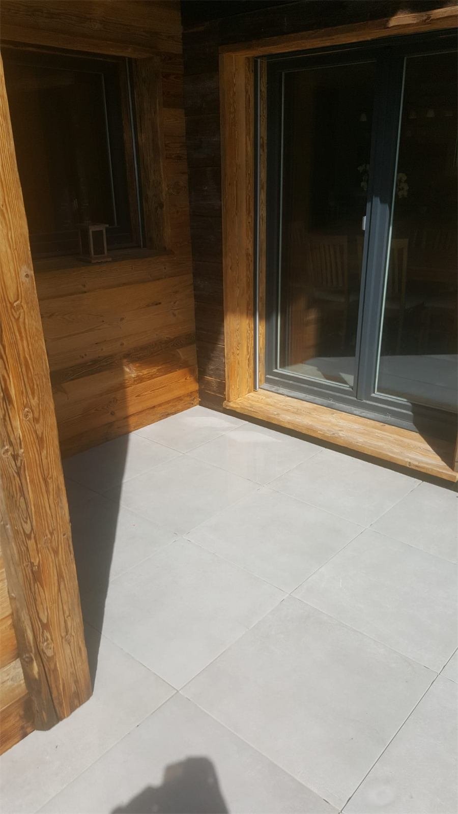 Terrasse carrelée devant une baie vitrée